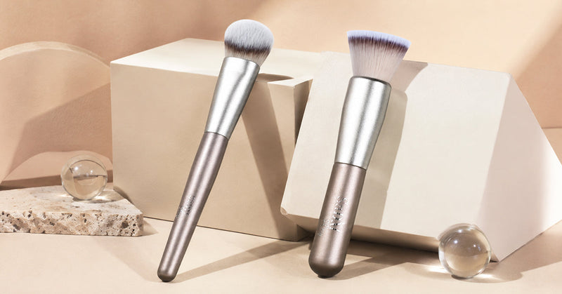 Flat foundation brush and angled foundation brush side by side with liquid foundation swatches