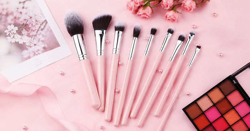 Flat lay of a simple beginner makeup brush set arranged beside everyday makeup products on a light background.