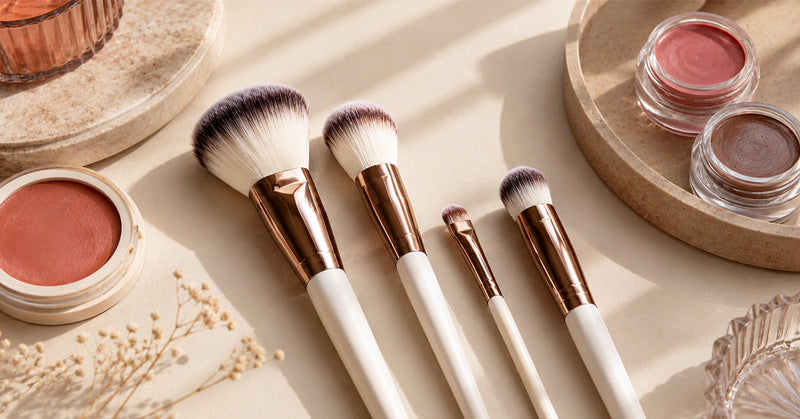 Makeup artist applying cream blush with a dense angled brush on a model’s cheek