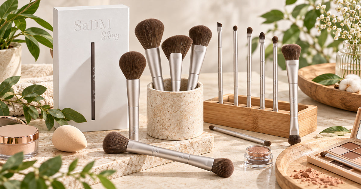 Flat lay of a vegan makeup brush set with soft synthetic bristles arranged beside neutral makeup products on a clean white background.